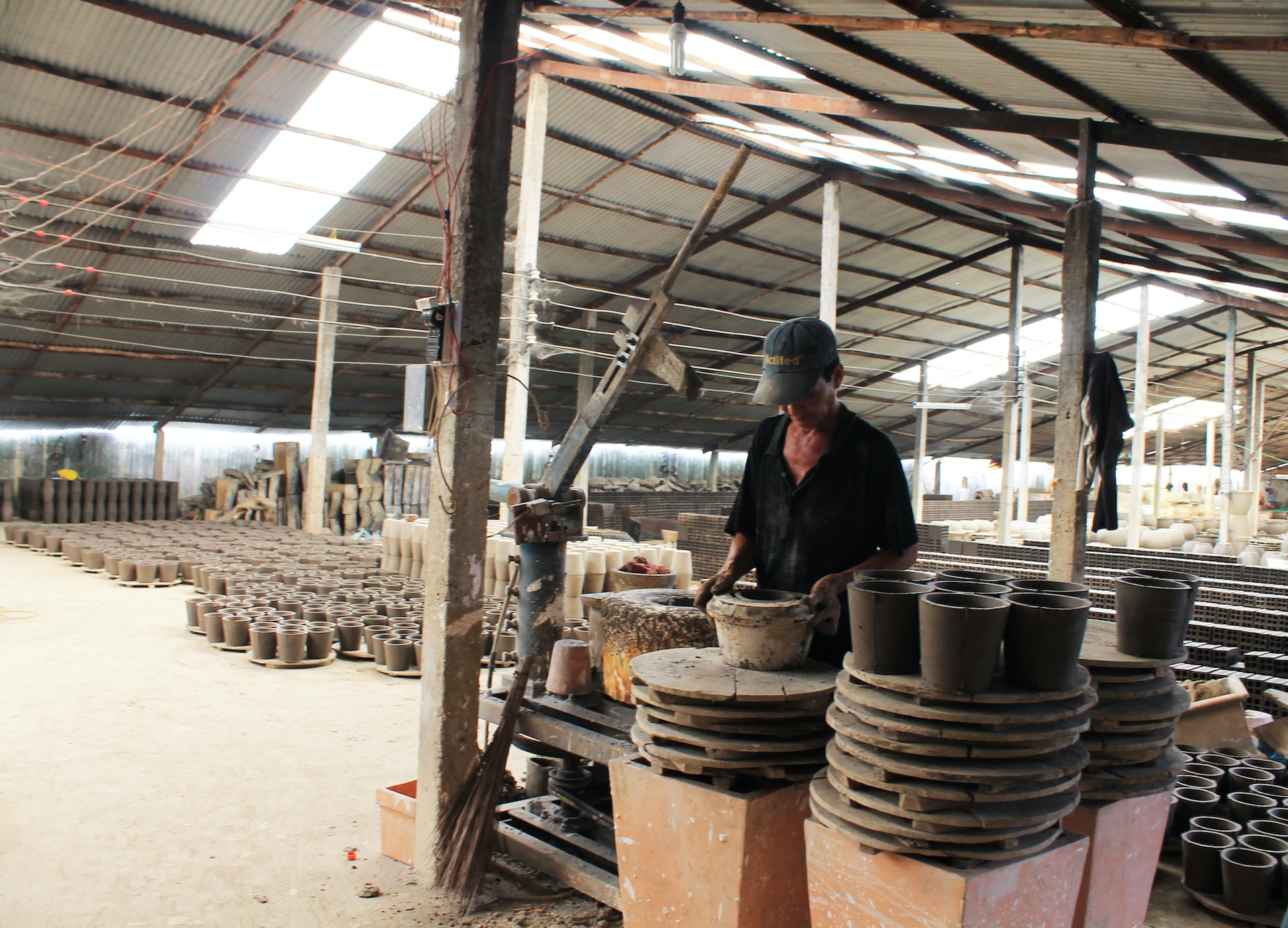 a man working in a factory with lots of pots